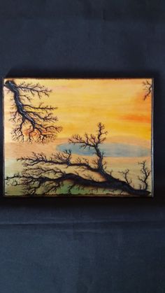 a painting is hanging on the wall next to a black cloth covered tablecloth with an orange and yellow sunset in the background