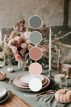 the table is set with pink and green plates, candles, flowers and pumpkins