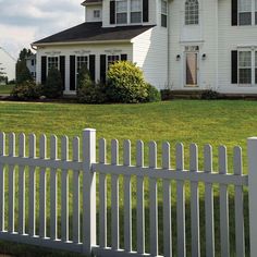 a white picket fence in front of a large house