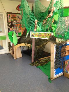 an indoor play area with green netting and toys on the floor, including a tree