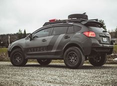 a grey car parked on top of a gravel road