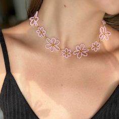 a woman wearing a pink necklace with flowers on it's neck and the bottom part of her chest