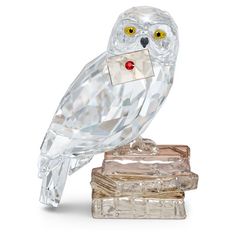 an owl figurine is sitting on top of some books and has yellow eyes