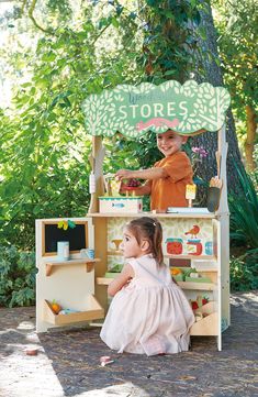 two young children are playing in an outdoor toy store