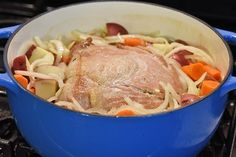 a blue pot filled with meat and veggies on top of a stovetop