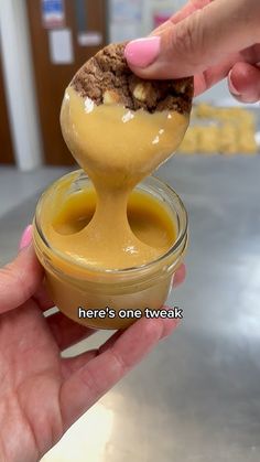 a person is dipping something into a jar filled with ice cream and caramel sauce