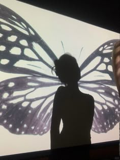 a woman standing in front of a butterfly projected on the wall with her hands behind her back