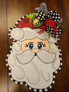 a santa claus face on a wooden floor with black and white polka dot ribbon around it