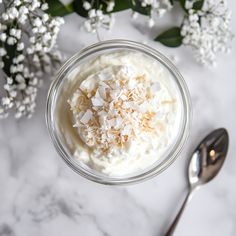 a glass bowl filled with whipped cream and coconut flakes on top of a marble counter