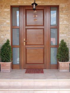 a wooden door with two planters on each side and a light fixture above it