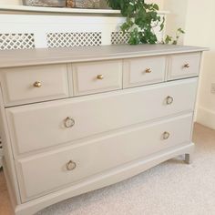 a white dresser sitting in a bedroom next to a plant on top of the dresser