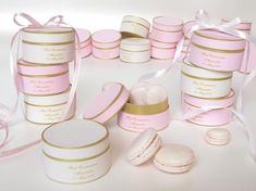 pink and gold wedding favors are arranged on a white surface with ribbon around the edges