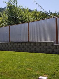 a boy is playing with a frisbee in the grass near a wall and fence