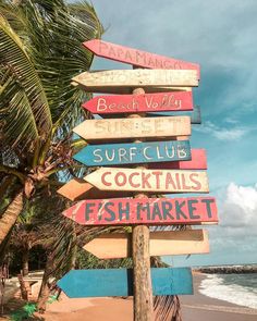 a wooden sign on the beach pointing in different directions