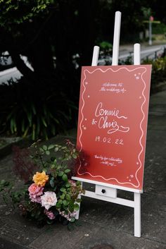 a wedding sign and flowers on the sidewalk