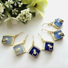 four pairs of earrings with blue and white squares on them next to some yellow flowers