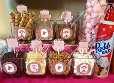 a table topped with lots of different types of snacks and candy bar signs on top of it