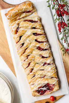 an image of a pastry on a cutting board with cherries and flowers in the background