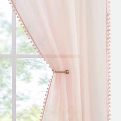 a pink curtain with pom - poms hanging from it's side in front of a window