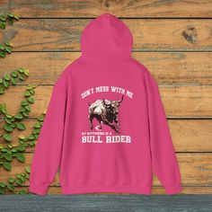 Introducing our cool new Ladies Rodeo Hoodie made just for adventurous gals like you! It's super comfy and has an awesome picture of a speedy bull on the back. Above the bull, there's a strong message saying "Don't Mess with Me," showing everyone you're a bold chick. Underneath the bull, in smaller letters, it playfully says, "My Boyfriend is a," and then, in big letters, "Bull Rider." This hoodie is not just about looking good but also about having fun and showing off your fearless side. Wear t Pink Long Sleeve Hoodie For Outdoor Activities, Pink Hoodie With Drawstring For Outdoor Activities, Casual Pink Hoodie For Outdoor Activities, Pink Cotton Hoodie For Outdoor, Casual Pink Sweatshirt For Outdoor Activities, Rodeo Girlfriend, Rodeo Wife, Wife Sweatshirt, Don't Mess With Me