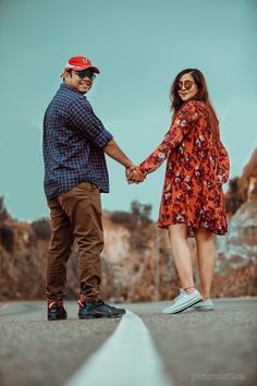 a man and woman holding hands while walking down the street