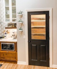 a kitchen with a black door and wooden flooring next to a stove top oven