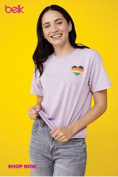 a smiling woman wearing a t - shirt with a rainbow heart on the front and side