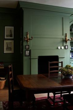 a dining room with green walls and wooden table in front of the fire place on the wall