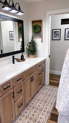 a large bathroom with wooden cabinets and white counter tops, along with pictures on the wall