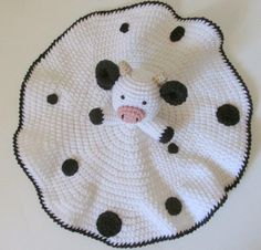 a crocheted cow with black spots on it's face sitting on a white surface