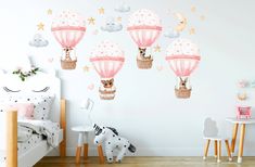 a child's bedroom decorated in pink and white with hot air balloons, animals and stars on the wall