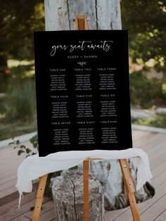 a wooden easel with a seating chart on it sitting in front of a tree