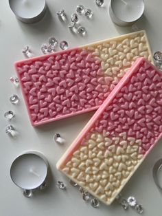 two pink and white cookies sitting on top of each other next to some silver candles