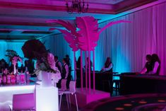 people are sitting at tables in a room with purple lighting and decorations on the walls