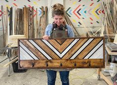 a woman holding up a large piece of art made out of wood and metal strips