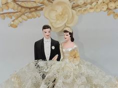 a cake topper with a bride and groom on it next to a bouquet of flowers