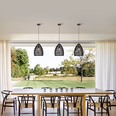 a table and chairs in front of an open window with the view of a grassy field