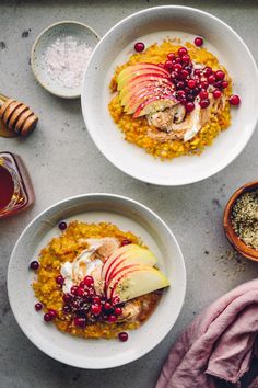 two bowls filled with food on top of a table next to honey and spoons