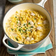 a pot filled with pasta and chicken on top of a wooden table