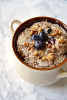 a bowl of oatmeal with blueberries and walnuts in it on a table