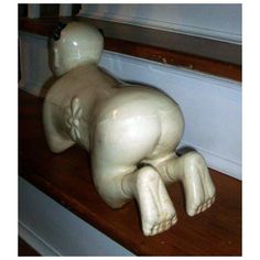 a white ceramic dog figurine sitting on top of a wooden window sill