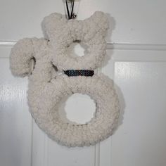 a white teddy bear wreath hanging on a door