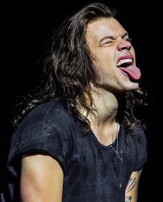 a man with long hair and piercings on his tongue is making a funny face