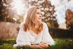 a woman sitting in the grass with her eyes closed and looking off into the distance