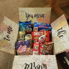 an open box filled with snacks on top of a floor next to a book and map