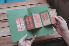 a person holding an open book on top of a wooden table