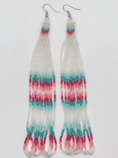 two pairs of multicolored seed beaded earrings with silver hooks on white background