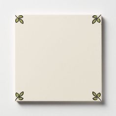 a square white tile with green leaves on the edges and border around it, against a white background