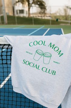 a t - shirt that says cool mom social club hanging on a tennis court net