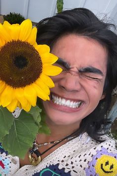 a smiling woman holding a sunflower in front of her face